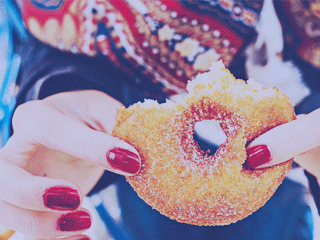 Hand with red fingernails holding a donut (to represent a nail-biter climax)