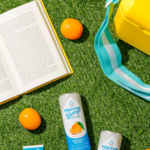 Summer image with book, bag, and oranges on the grass